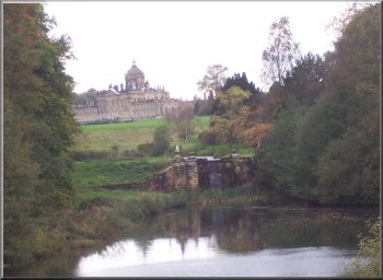 A view of Castle Howard house through the trees from the bridge